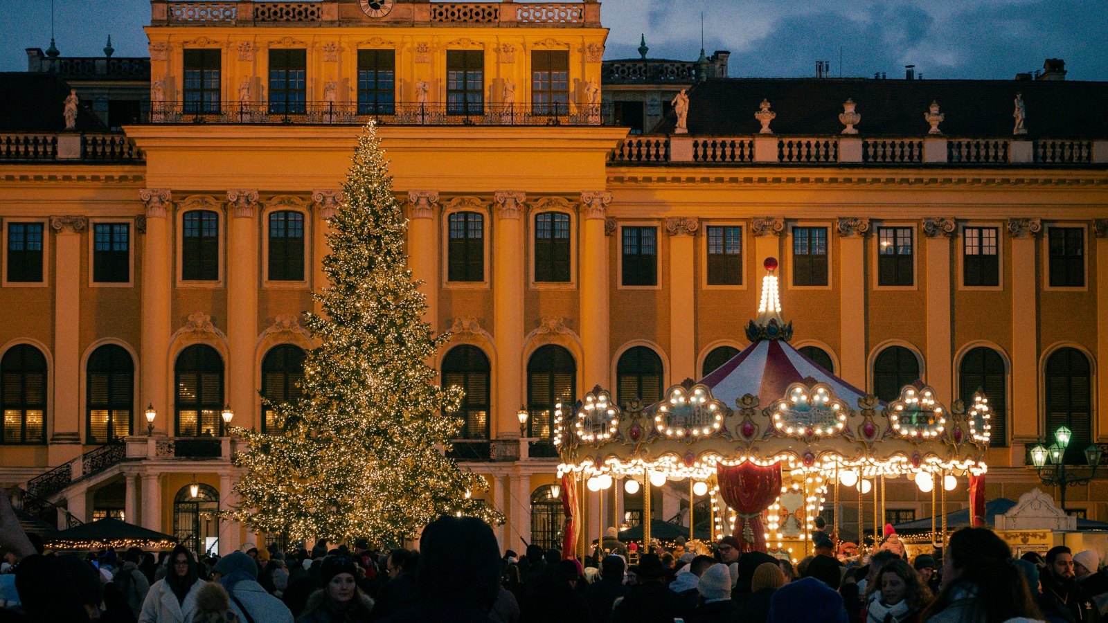 Christmas tree and market stalls in front of a lit palace