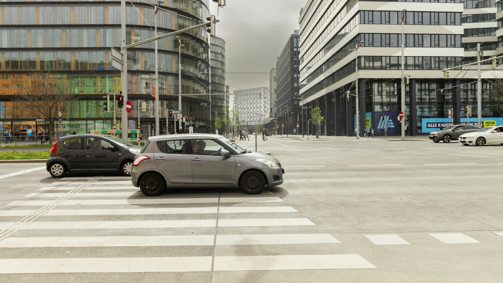 Cars crossing a wide city intersection between modern buildings