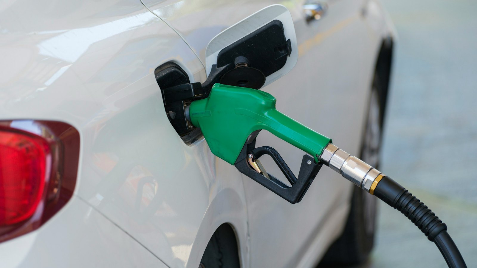 Fuel nozzle in the open fuel flap of a white car